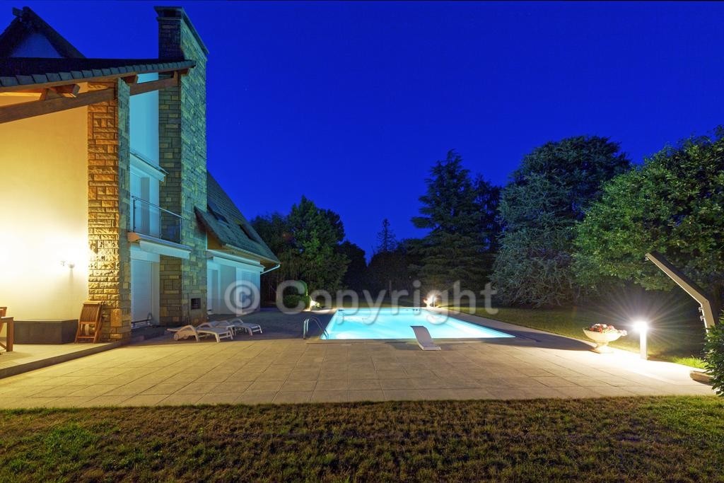 Maison d'architecte éclairée le soir avec piscine