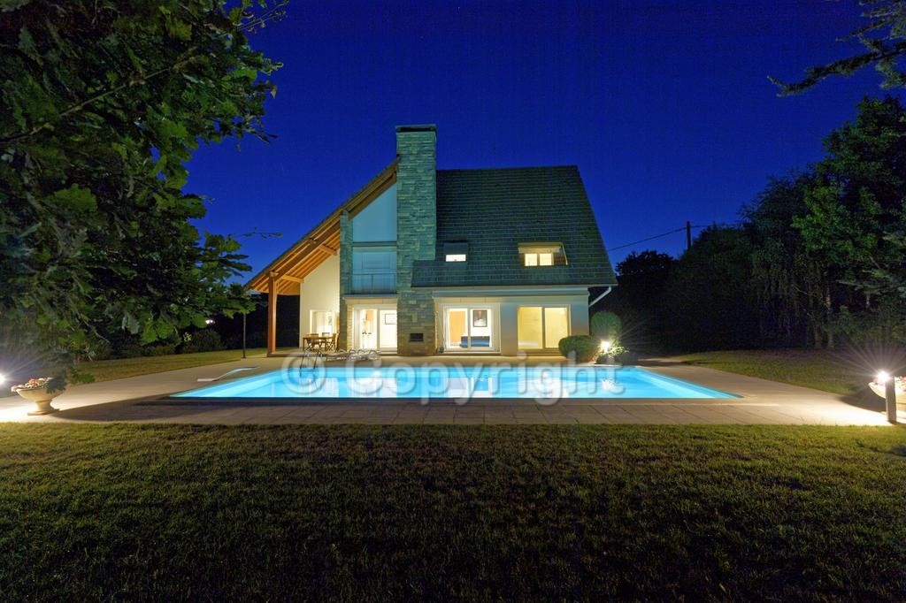 Maison d'architecte et piscine éclairées de nuit