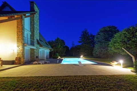 Maison d'architecte éclairée le soir avec piscine